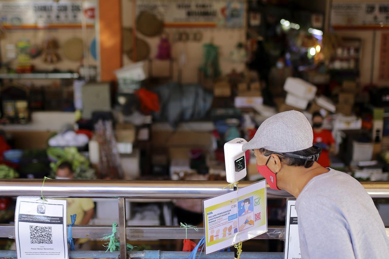 A customer checks his temperature before entering a market in Seremban, Negeri Sembilan. Photo: Bernama