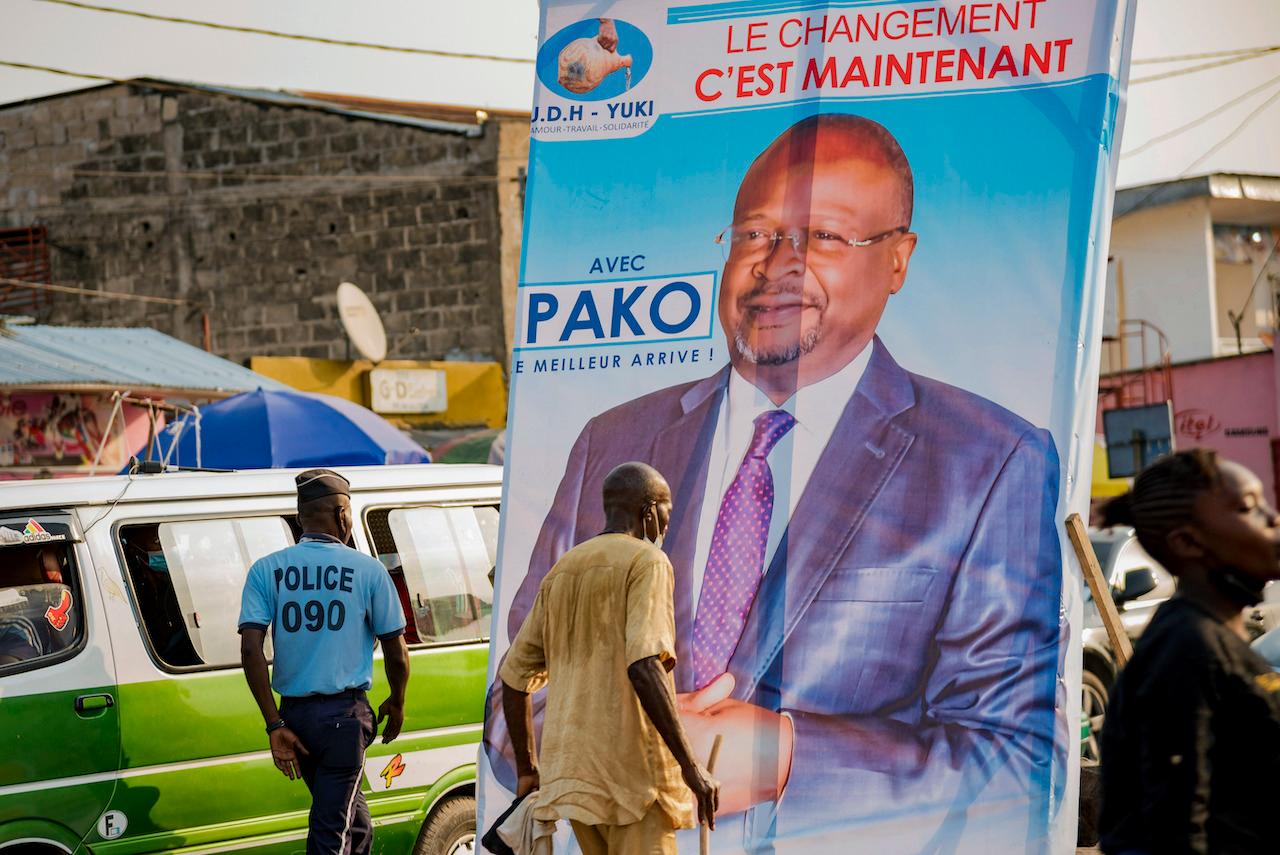 People walk past an election poster featuring opposition presidential candidate Guy Brice Parfait Kolelas, in downtown Brazzaville, Congo on March 7. Kolelas, who was hospitalised with Covid-19 complications on election day, has died, a spokesman said Monday. Photo: AP