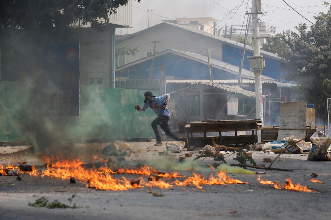 A man runs past a road barricade and burning debris in Mandalay, Myanmar, March 22. More than 260 people have been killed since nationwide protests erupted against the coup, according to a local monitoring group. Photo: AP