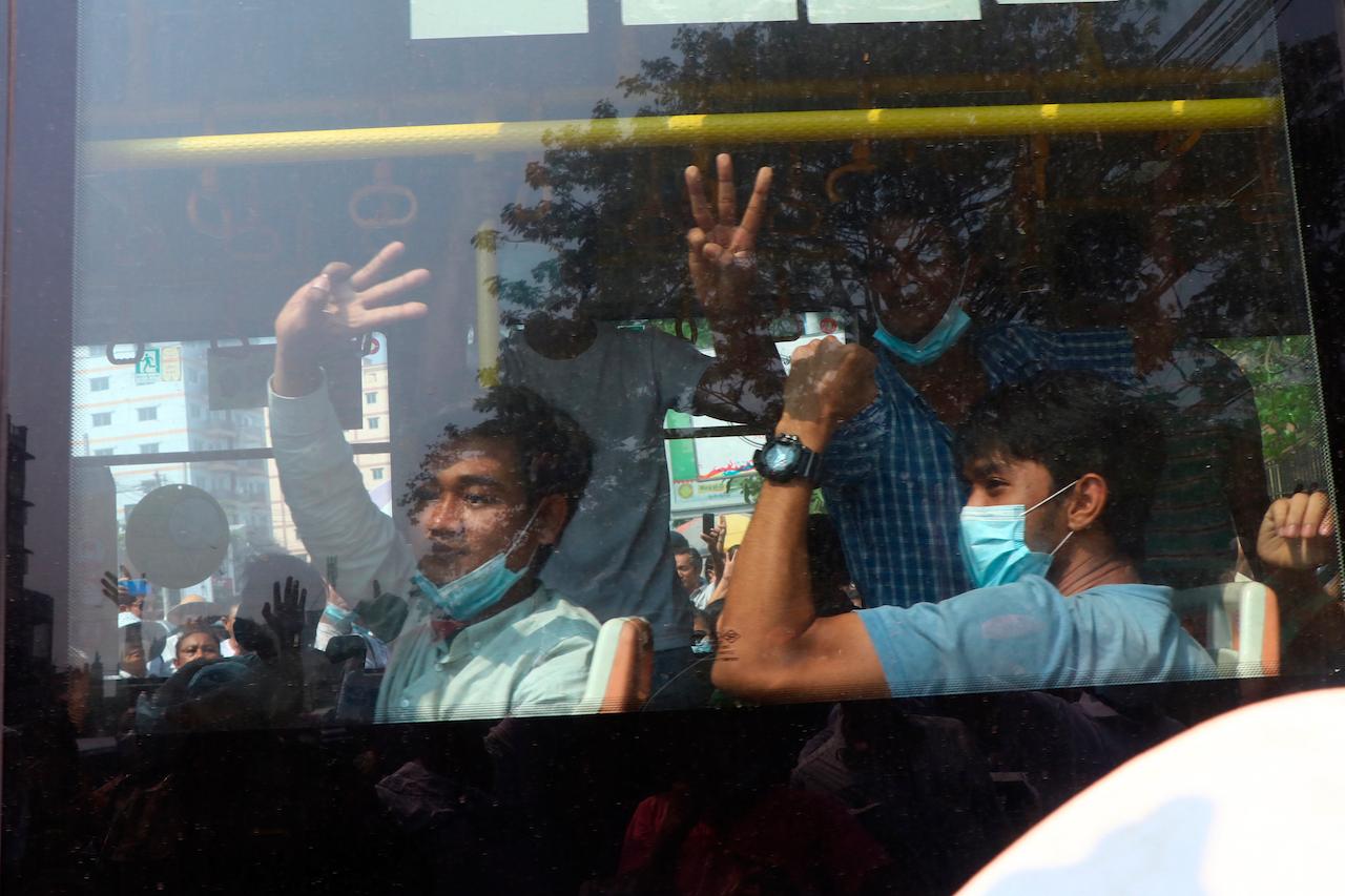 Protesters flash the three-fingered salute while onboard a bus departing Insein prison in Yangon, Myanmar, March 24. Photo: AP