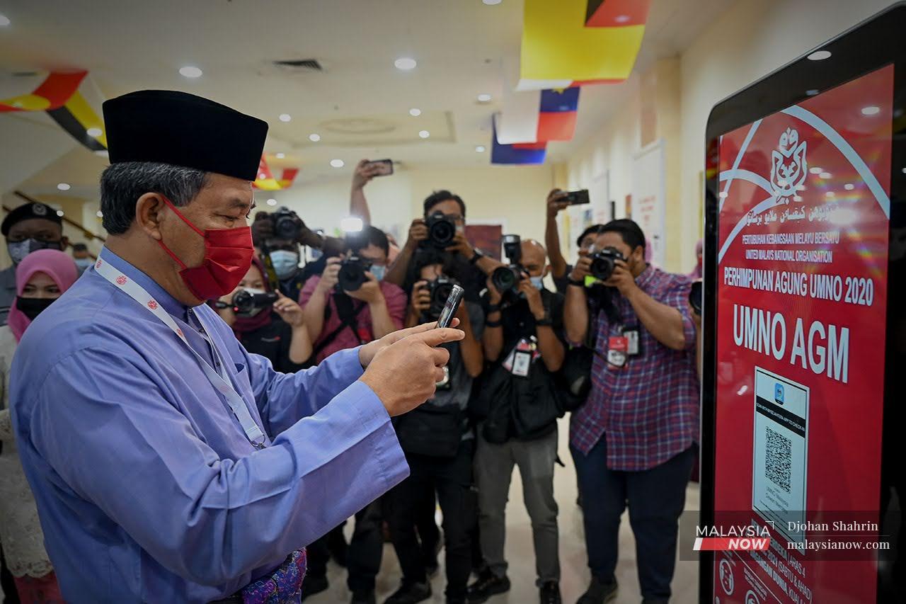 Timbalan Presiden Umno, Mohamad Hassan membuat imbasan kod mySejahtera sebelum masuk ke Dewan Merdeka bagi perasmian Persidangan Umno 2021 di Pusat Dagangan Dunia Putra.