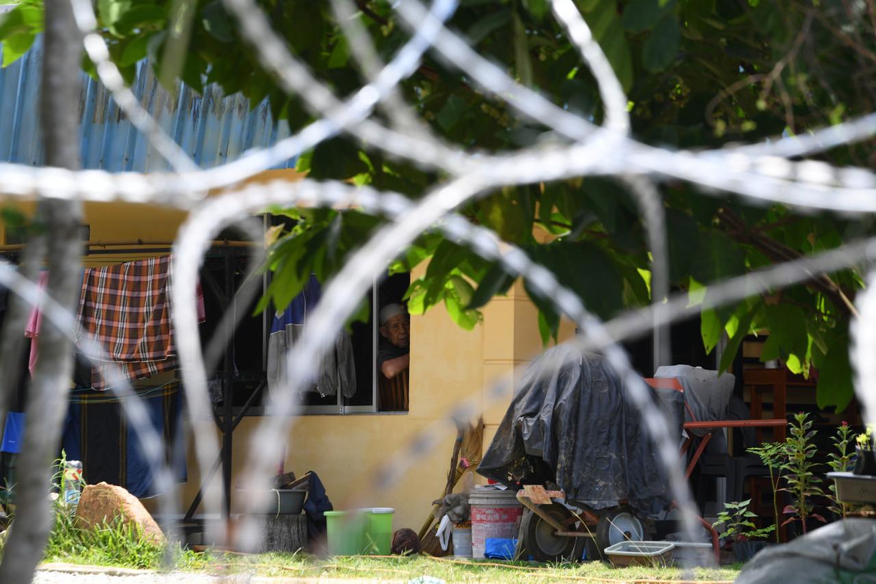 A resident of Taman Guru in Kuantan, Pahang, looks out his window at the barbed wire fence put up around the neighbourhood in the wake of an increase in Covid-19 cases in the area. Photo: Bernama