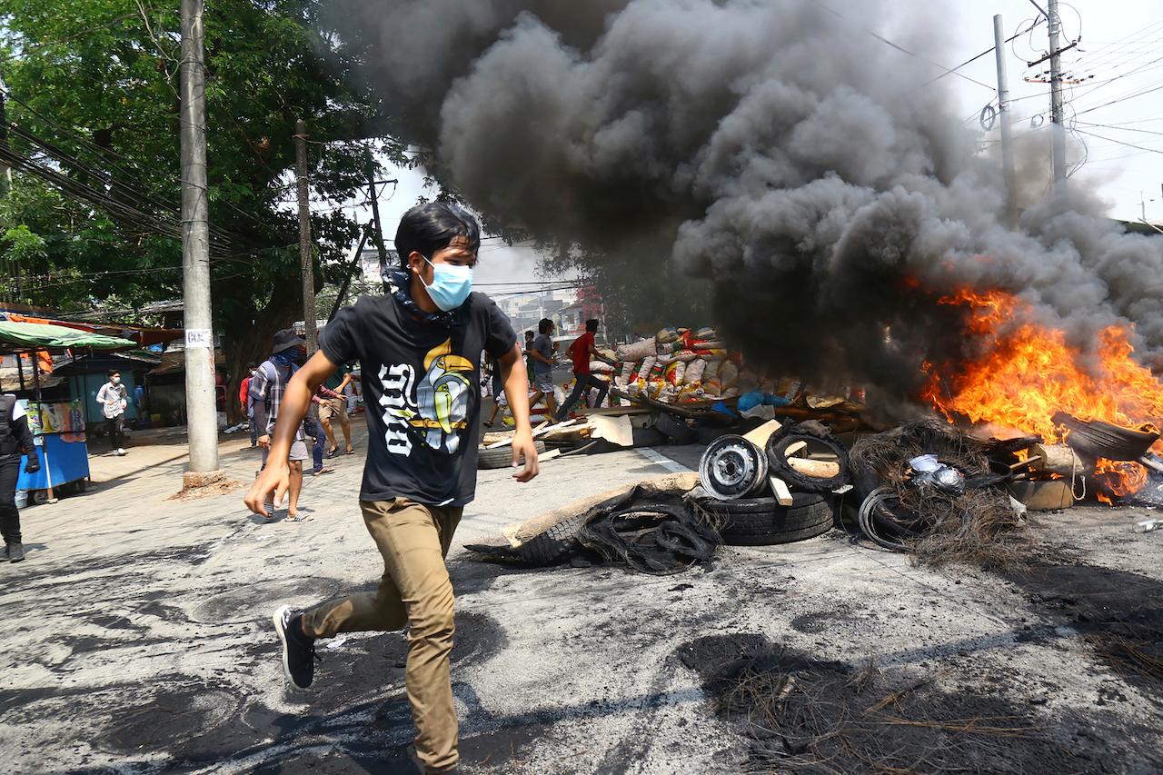 Anti-coup protesters run around their makeshift barricade they burn to make defence line during a demonstration in Yangon, Myanmar, March 28. Protesters in Myanmar returned to the streets Sunday to press their demands for a return to democracy, just a day after security forces killed more than 100 people in the bloodiest day since last month's military coup. Photo: AP