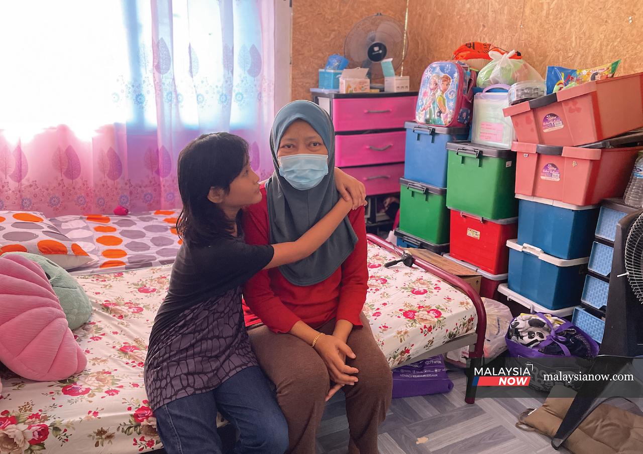 Nur Fatihah Sahminan embraces her mother, Norlela Bujang, in their small rented room in Kuching, Sarawak, where their belongings are lined up against a wall. The two depend on financial aid from the government as well as from NGOs in order to make ends meet.