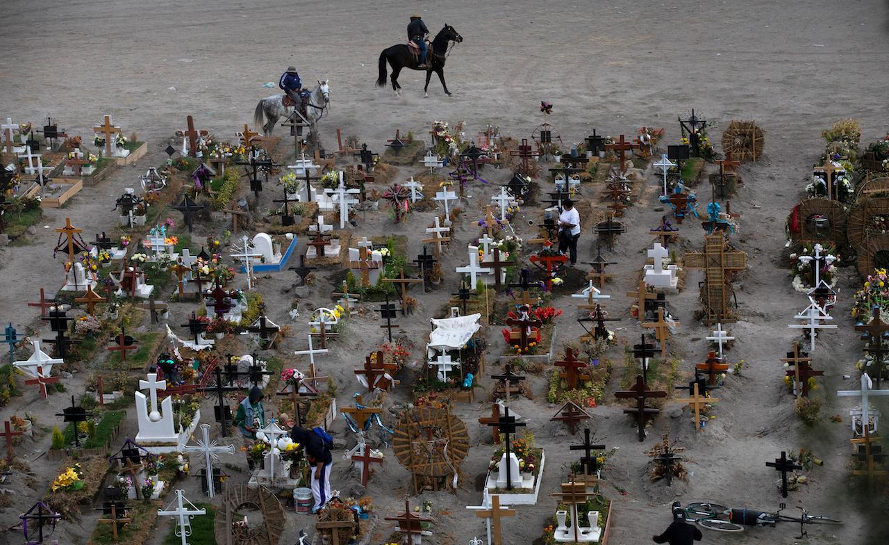 Workers ride their horses in the Valle de Chalco municipal cemetery, mostly reserved for those who have died from the coronavirus, on the outskirts of Mexico City, Nov 18, 2020. Experts have long warned that Mexico's true death toll is probably much higher due to a lack of testing. Photo: AP