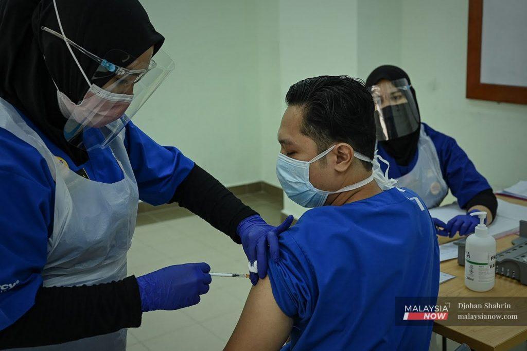 A health worker administers the first shot of the Pfizer-BioNTech vaccine to a frontliner at Hospital UiTM in Sungai Buloh, Selangor.