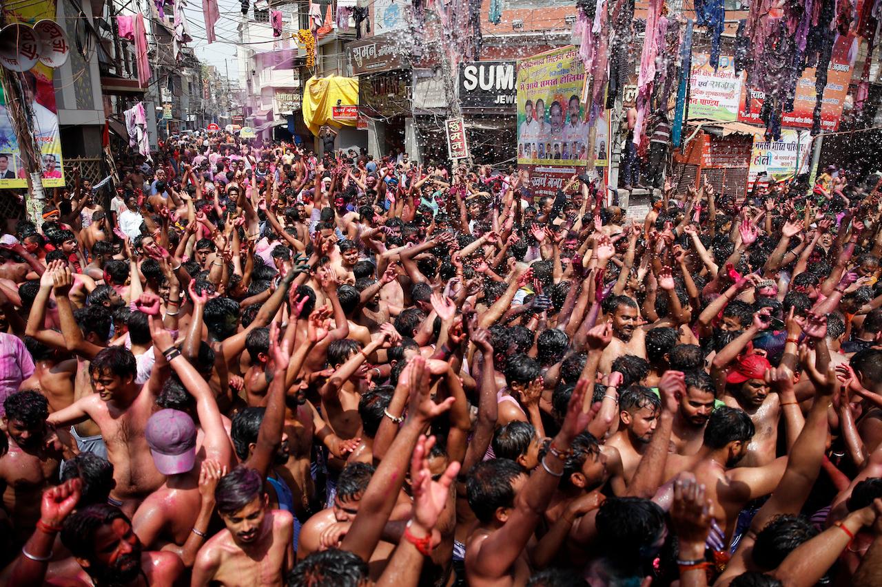 Indians, their faces smeared with colour and glitter, dance as water is sprinkled on them during Holi celebrations in Prayagraj, India, March 29. Hindus threw coloured powder and sprayed water in massive Holi celebrations Monday despite many Indian states restricting gatherings to try to contain a coronavirus resurgence rippling across the country. Photo: AP