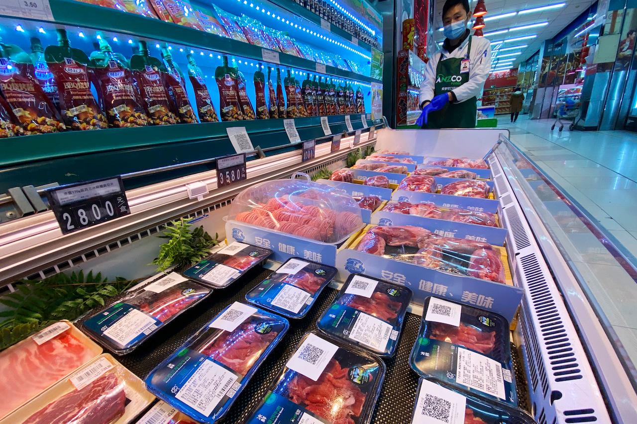 A worker wearing a mask and gloves stands near beef products from New Zealand packaged with a QR-code linked to its coronavirus test results displayed at a supermarket in Beijing, Nov 24, 2020. International health experts say the introduction of Covid-19 through frozen food would have been 'extraordinary' in December 2019 given the virus had not been detected elsewhere at that time. Photo: AP