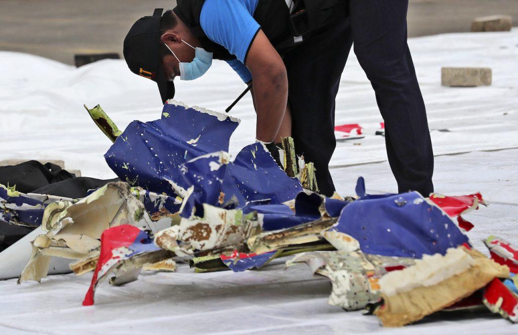 An investigator from the Indonesian National Transportation Safety Committee inspects parts of Sriwijaya Air flight 182 which crashed in the waters off Java Island, at Tanjung Priok Port in Jakarta, Jan 10. Photo: AP