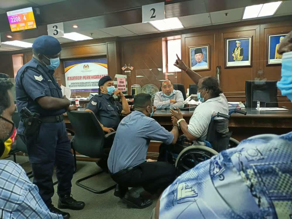 An activist from the Independent Living & Training Centre Malaysia speaks with officers and police at the welfare department in Kuala Lumpur.
