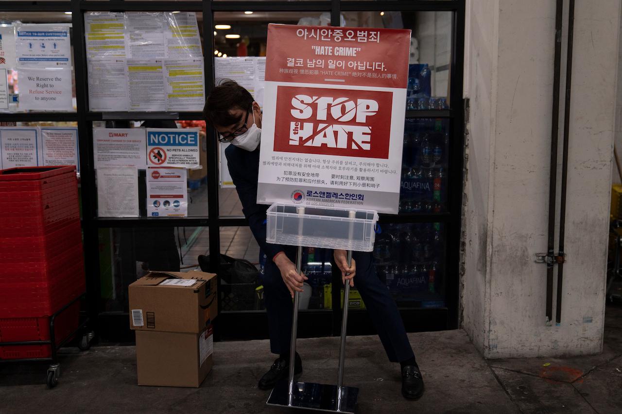 A member of the Korean American Federation of Los Angeles puts up a poster calling for a stop to anti-Asian hate crimes in the Koreatown neighbourhood of Los Angeles, March 23. Photo: AP