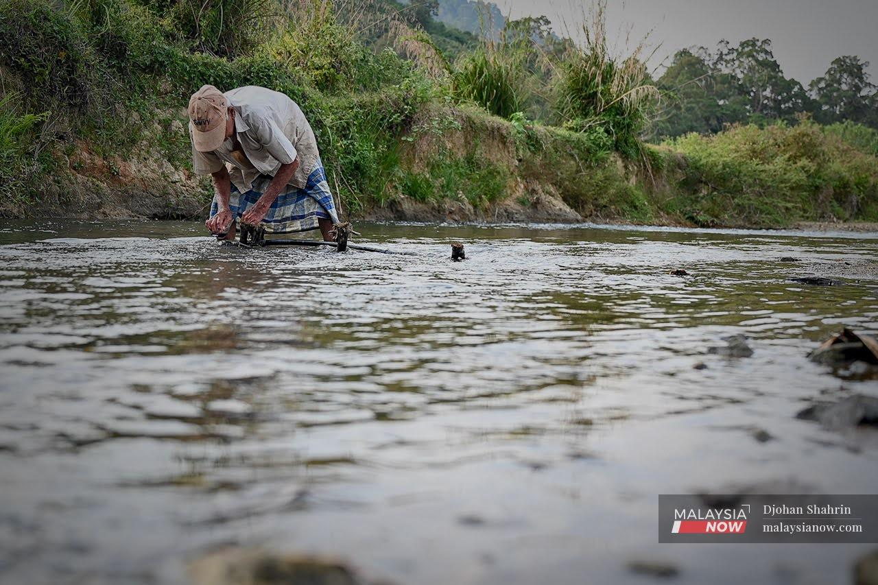 A villager checks a makeshift pipeline which carries water from the river to his home in Kampung Bukit Sebelah in Baling, Kedah.