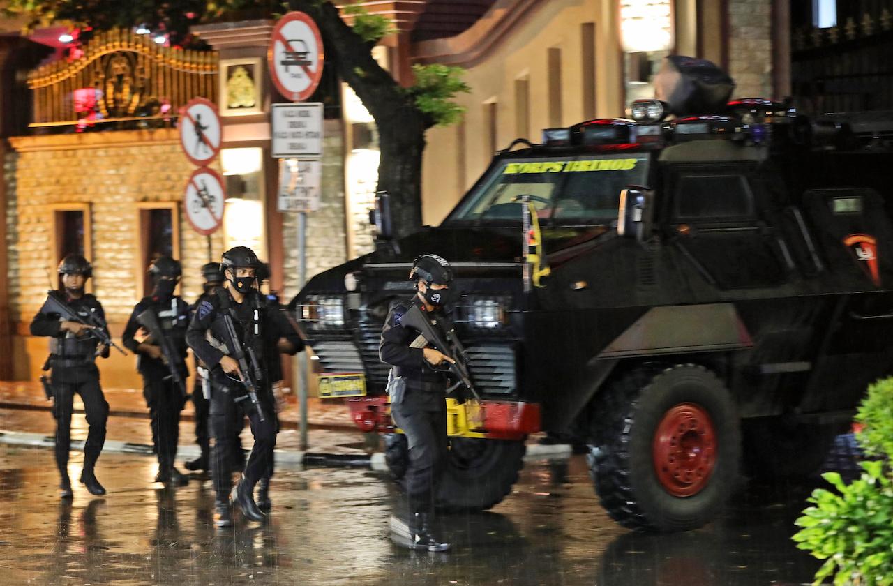 Police officers walk past an armored vehicle at the national police headquarters following a terror attack in Jakarta, Indonesia, March 31. The attack, the latest in the country, saw a woman entering the national police headquarters and pointing a gun at several officers before being shot dead by police. Photo: AP