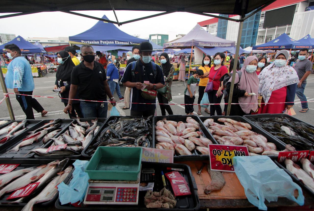 Customers adhere to health SOPs at a fish stall at a farmers market in Kuantan, Pahang, today. Photo: Bernama