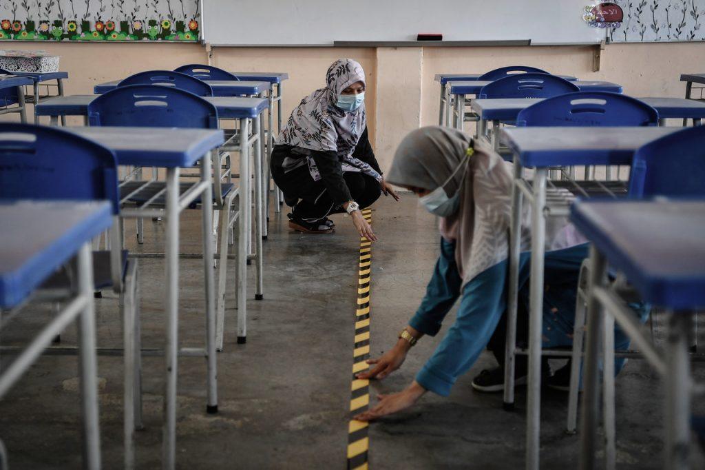 Teachers use tape to mark off areas on a classroom floor to facilitate physical distancing among students as part of health SOPs to curb the spread of Covid-19. Photo: Bernama