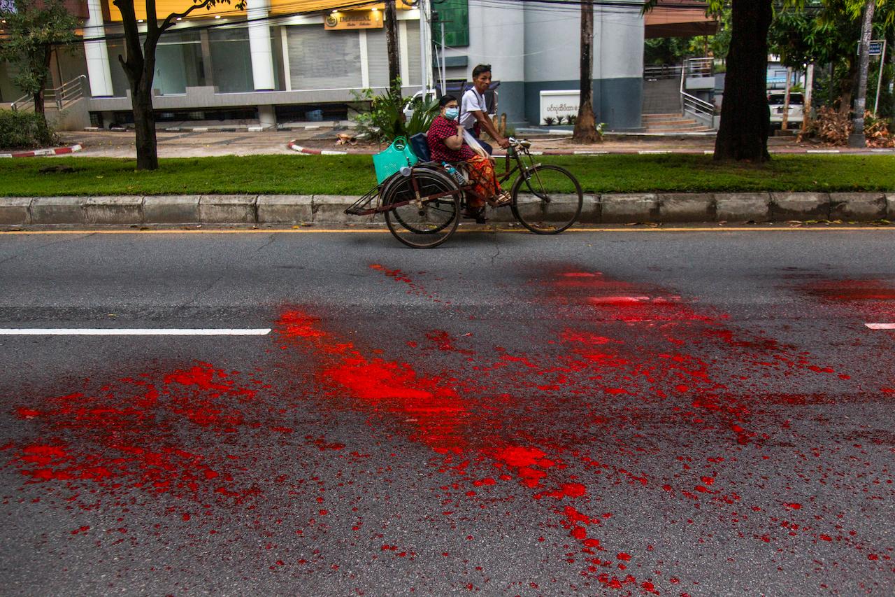 A woman riding a rickshaw passes by a street with splashes of red paint from anti-coup protesters during a demonstration in Yangon, Myanmar, April 6. Threats of lethal violence and arrests of protesters have failed to suppress daily demonstrations across Myanmar demanding the military step down and reinstate the democratically elected government. Photo: AP
