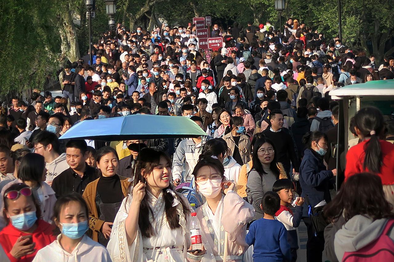 Visitors wearing face masks to protect against Covid-19 walk across a causeway at the West Lake in Hangzhou in eastern China's Zhejiang province, April 4. China reported just 11 domestically transmitted cases on Thursday, while life has returned largely to normal in most parts of the country. Photo: AP