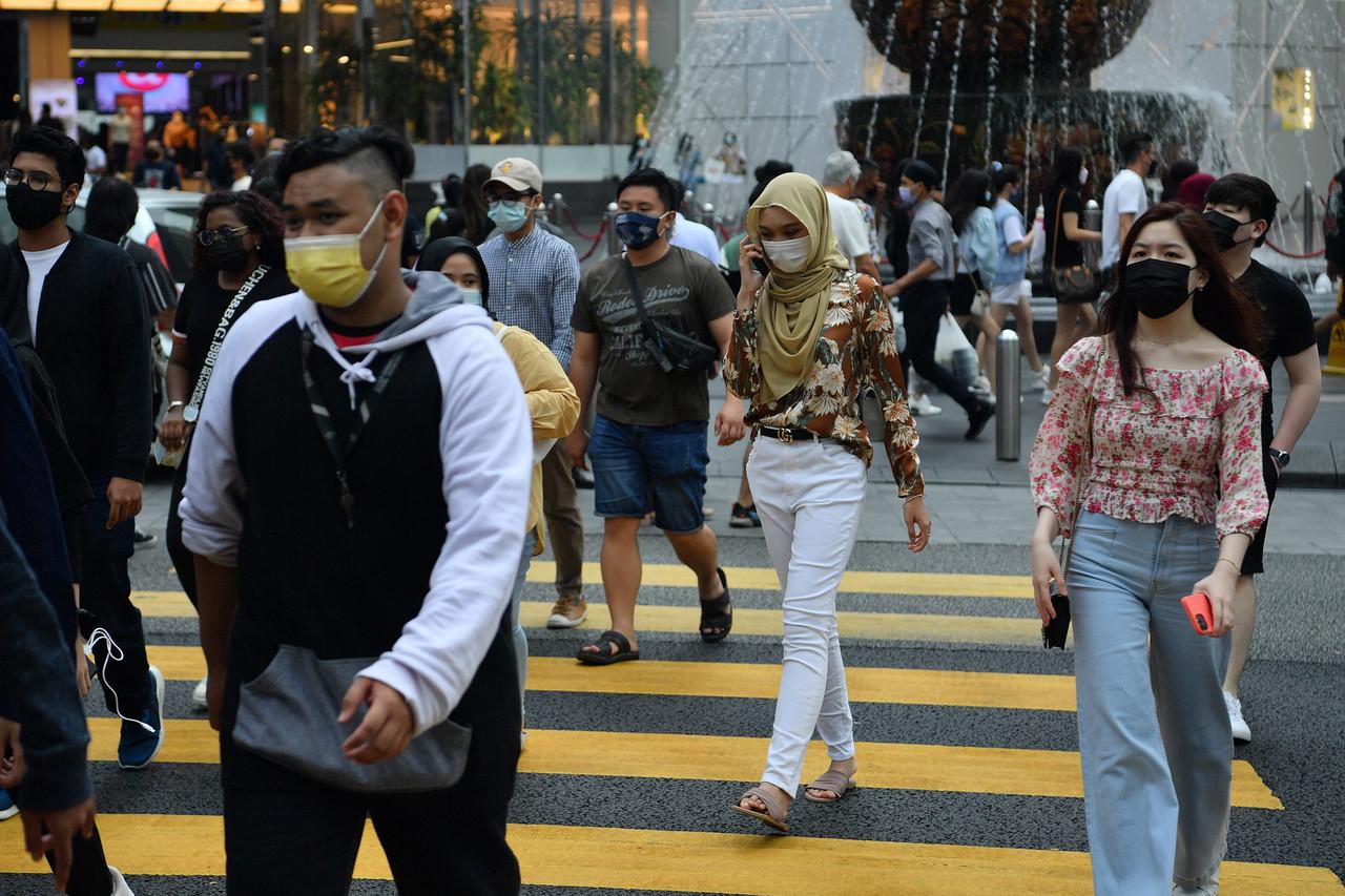 Pedestrians wearing face masks to curb the spread of Covid-19 cross a road in Kuala Lumpur. Photo: Bernama
