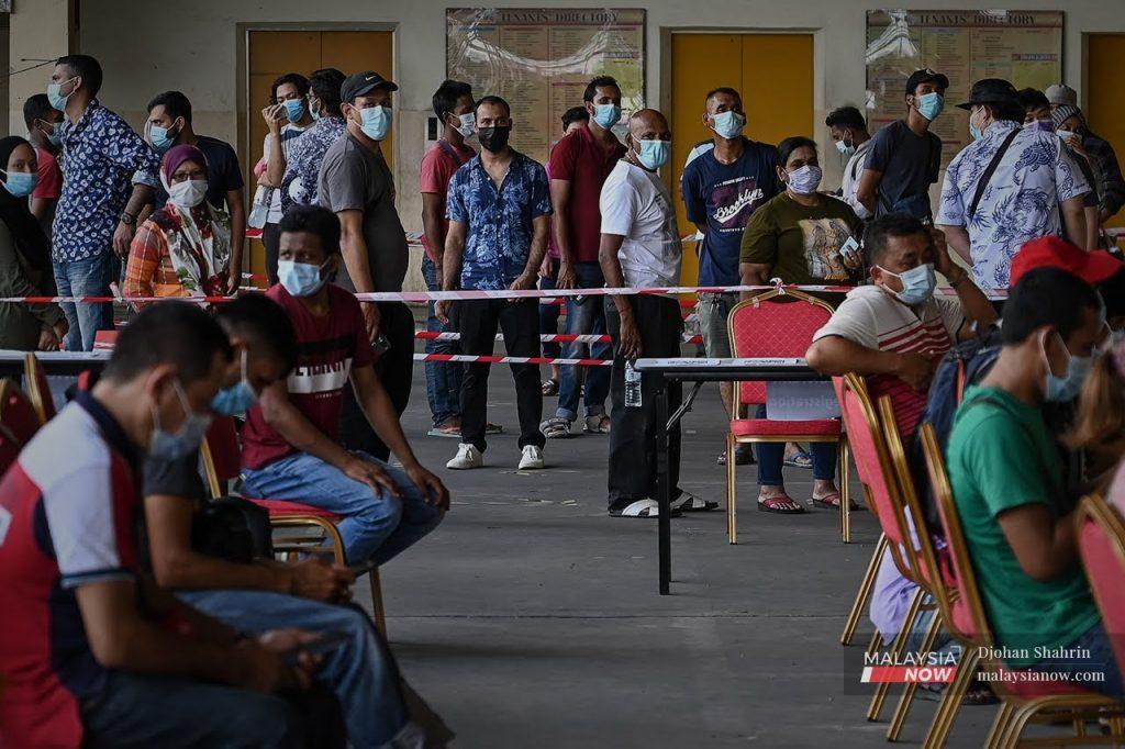 Foreign workers wait in line to be swabbed for Covid-19 at a clinic in Taman Connaught, Cheras.