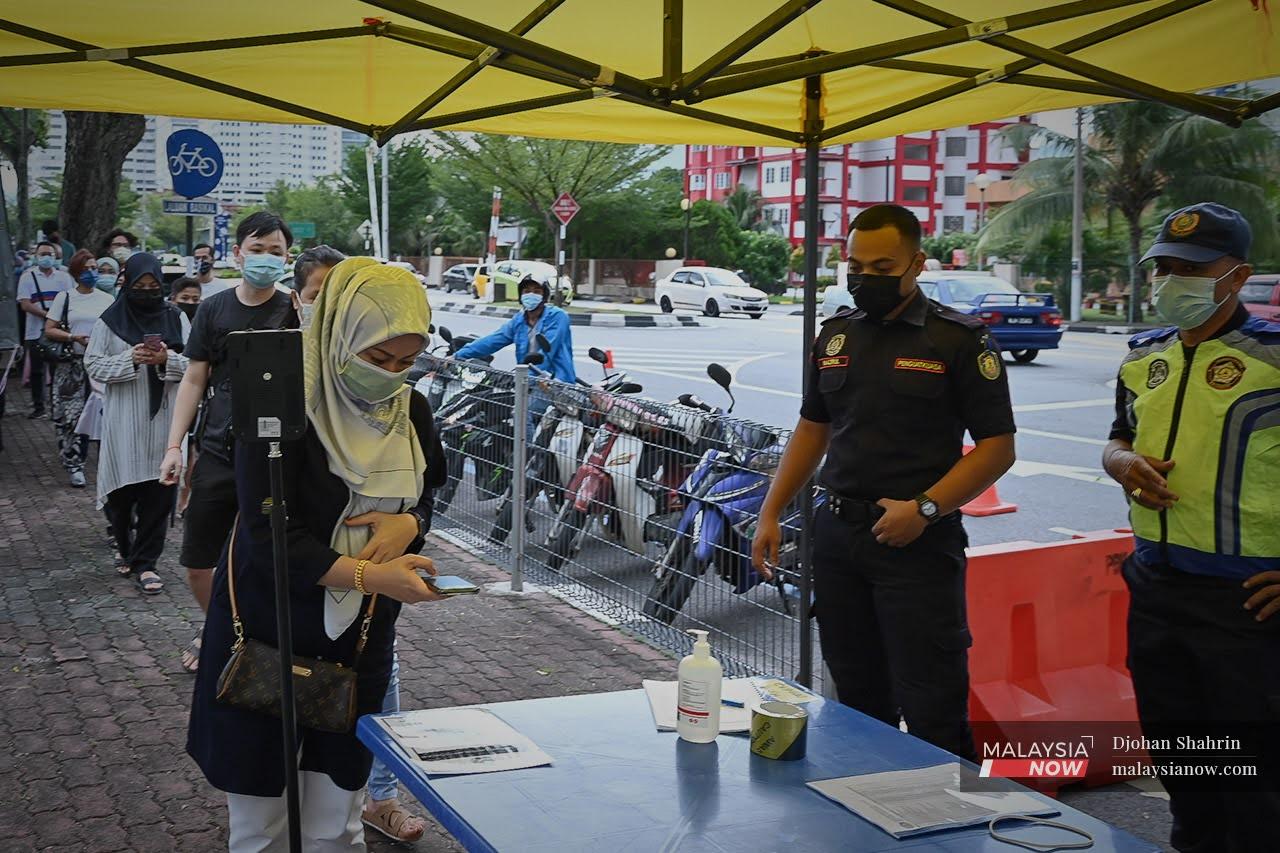 Customers queue to check their temperatures and scan the QR code at a Ramadan bazaar in Pandan Indah, Kuala Lumpur.