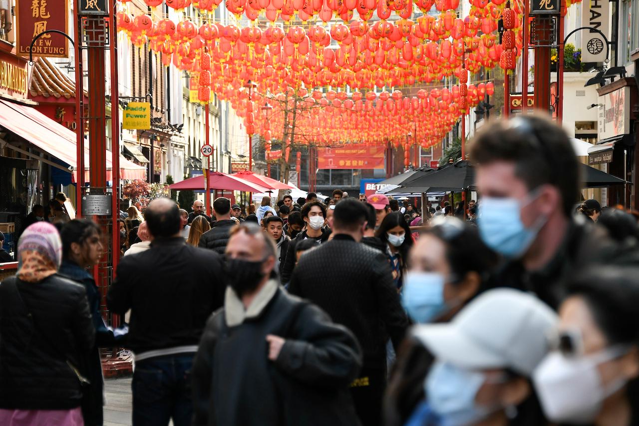 People walk and queue outside restaurants in Chinatown, in London, April 17, as shops, gyms, hairdressers, restaurant patios and beer gardens reopened Monday after months of lockdown. Photo: AP