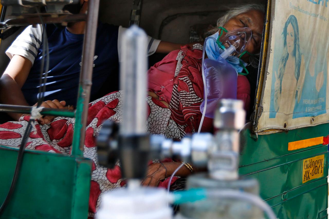 A Covid-19 patient wearing an oxygen mask waits inside an auto rickshaw to be attended and admitted to a dedicated Covid-19 government hospital in Ahmedabad, India, April 17. The global death toll from the coronavirus topped a staggering three million people Saturday amid repeated setbacks in the worldwide vaccination campaign and a deepening crisis in places such as Brazil, India and France. Photo: AP