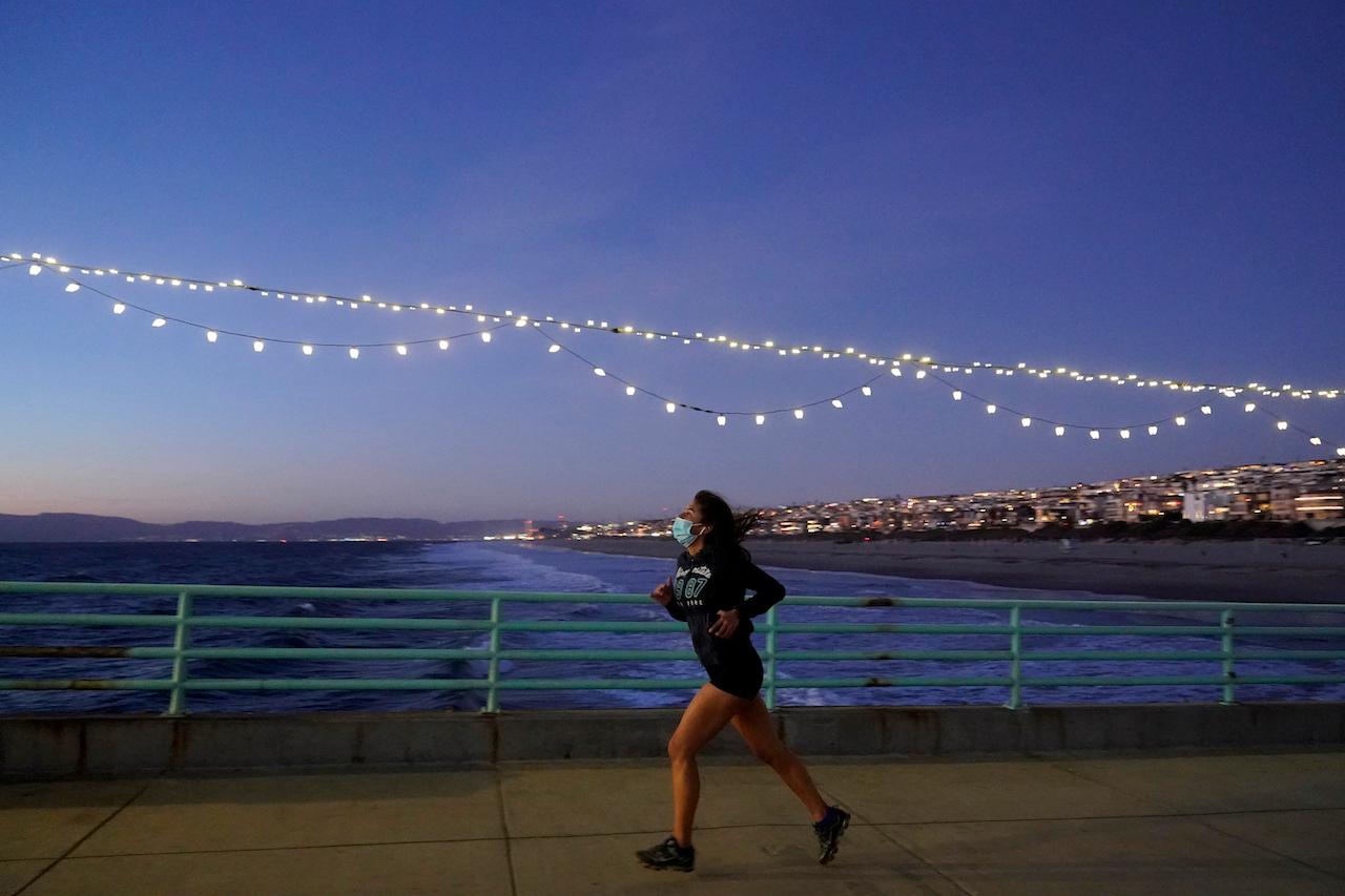 A woman jogs while wearing a face mask on the pier at the Manhattan Beach section of Los Angeles, Dec 14, 2020. Top health experts now believe that Covis-19 is primarily airborne, which makes outdoors much safer than indoors. Photo: AP