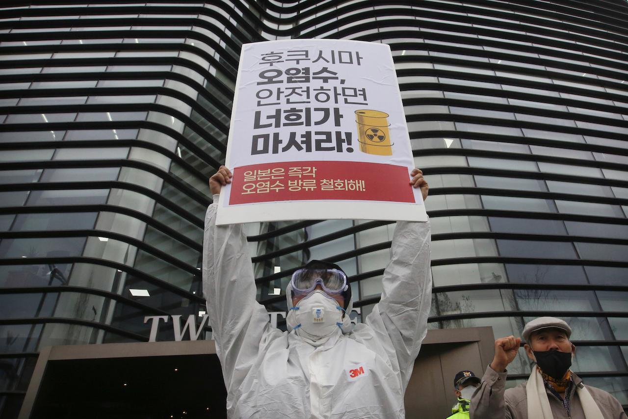 A member of a citizens' group holds up a banner during a rally to denounce the Japanese government's decision on releasing treated radioactive water from the wrecked Fukushima nuclear plant into the Pacific Ocean, in front of the building housing the Japanese embassy in Seoul, South Korea, April 16. Photo: AP