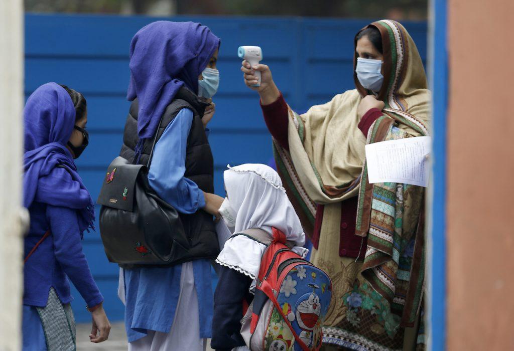 Guru memeriksa suhu pelajar ketika mereka hadir di sekolah di Pakistan. Gambar: AP