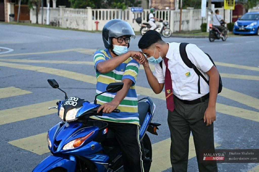 Pelajar sekolah dihantar bapa menaiki motosikal ke sekolah. Sesi persekolahan perlu dijalankan dengan SOP ketat bagi mengelakkan jangkitan Covid-19.