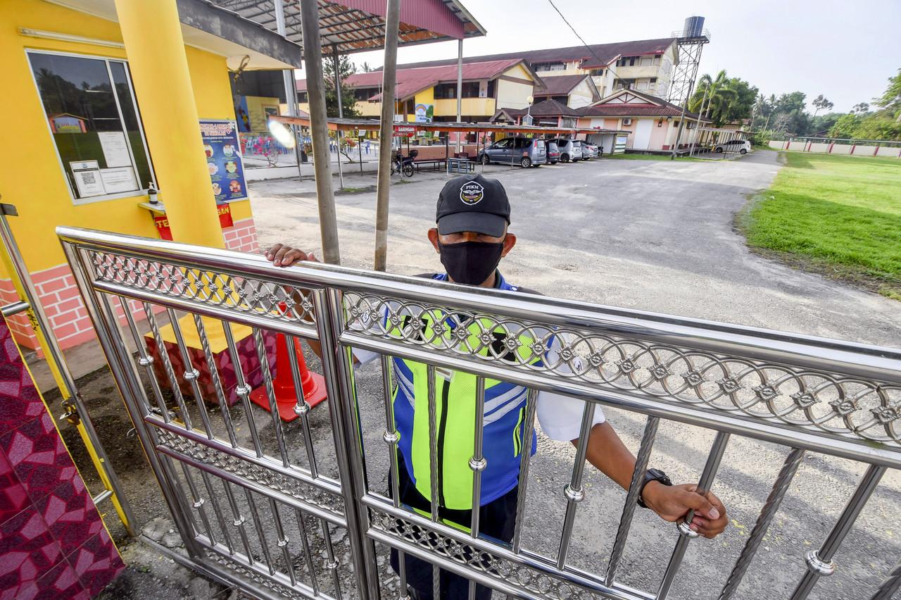 A security guard at SK Pasir Hor in Kota Bharu, Kelantan, closes the gate of the school which was ordered to close on April 18. Photo: Bernama