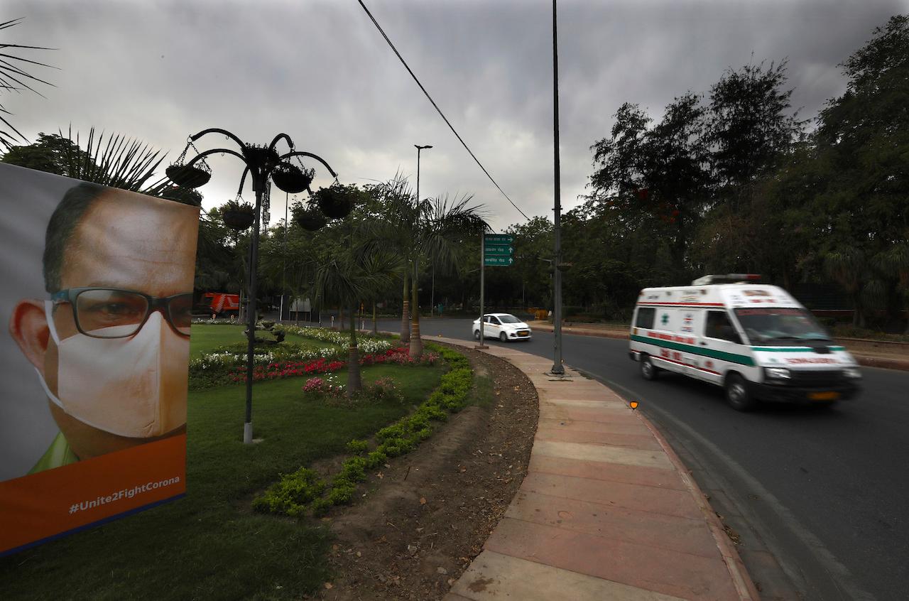 An ambulance carrying a patient drives past a coronavirus awareness poster on a deserted street on the first day of a six-day lockdown put in place to control the rising cases of Covid-19 infections, in New Delhi, India, April 20. Photo: AP