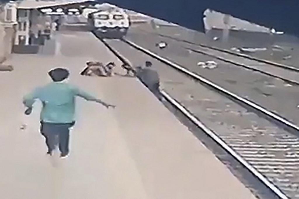 This video frame grab taken from footage released by the Indian railways ministry on April 20 shows pointsman Mayur Shelke (right) saving a child (top centre) who had lost his balance and fell in the path of an oncoming train at the Vangani railway station in Mumbai. Photo: AFP