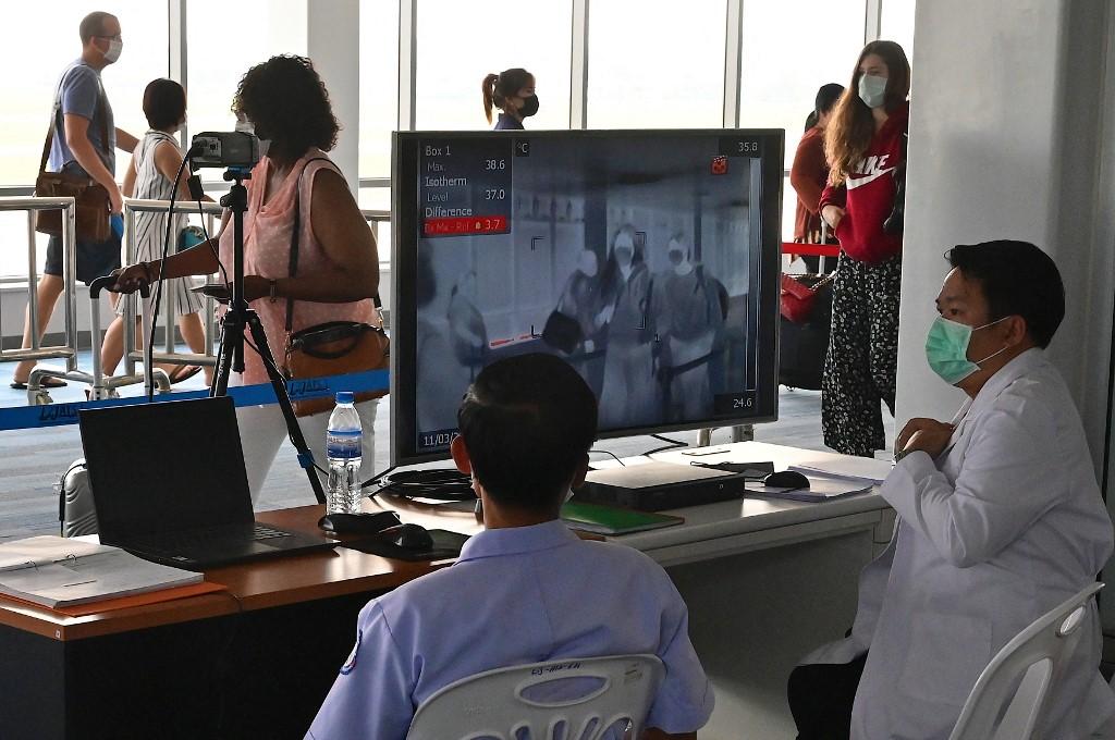 Passengers pass in front of a temperature screening camera at the arrivals area of Wattay International Airport in Vientiane on March 11, 2020. The country’s international borders are now closed except to trucks carrying goods and in cases specifically permitted by the nation’s Covid-19 taskforce. Photo: AFP
