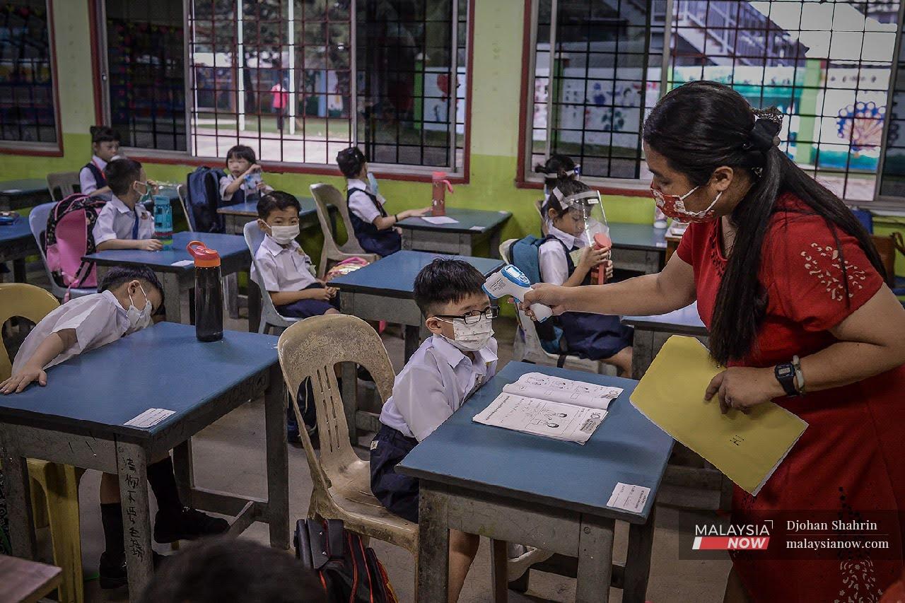 Guru mengambil suhu murid-murid ketika berada didalam kelas di Sekolah Jenis Kebangsaan Cina Khai Chee, Segambut. SOP perlu dipatuhi setiap institusi pendidikan bagi membendung Covid-19.