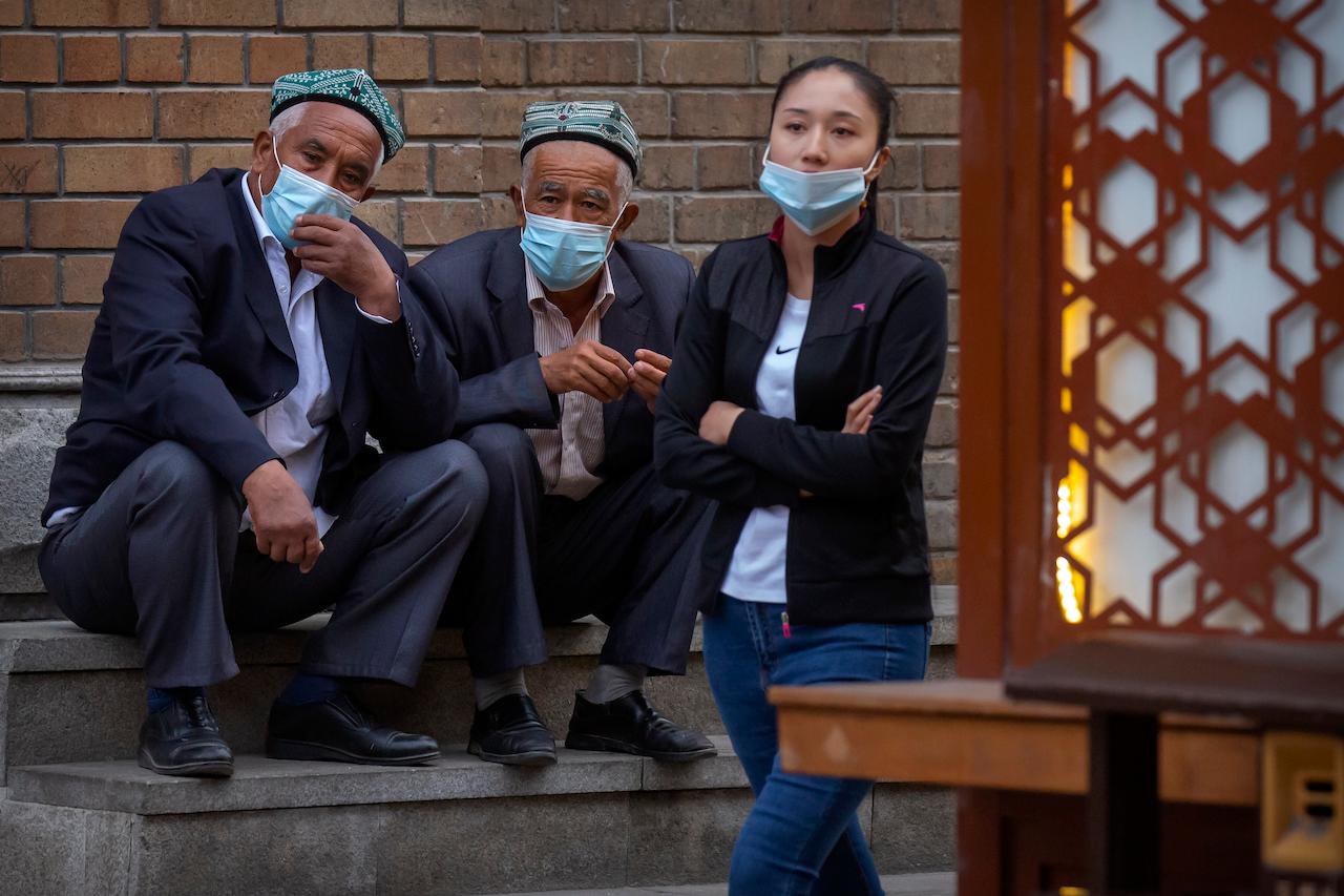 Uighur men sit on the steps of the International Grand Bazaar in Urumqi in western China's Xinjiang Uighur Autonomous Region, April 21. Photo: AP