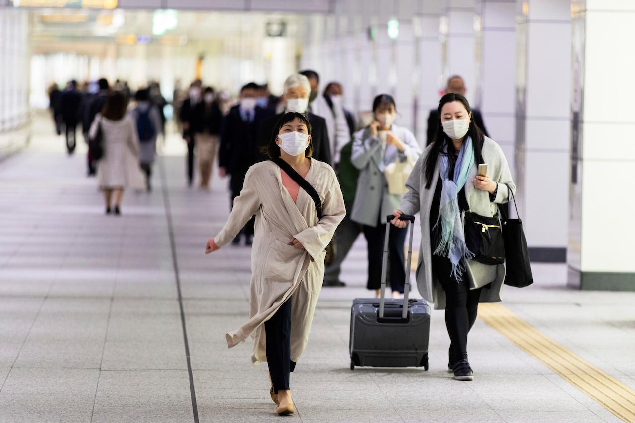 People wearing face masks to help curb the spread of the coronavirus walk towards a train station in Tokyo, April 23. Tokyo is one of four regions that will be placed under a state of emergency as Japan battles a surge in infections. Photo: AP
