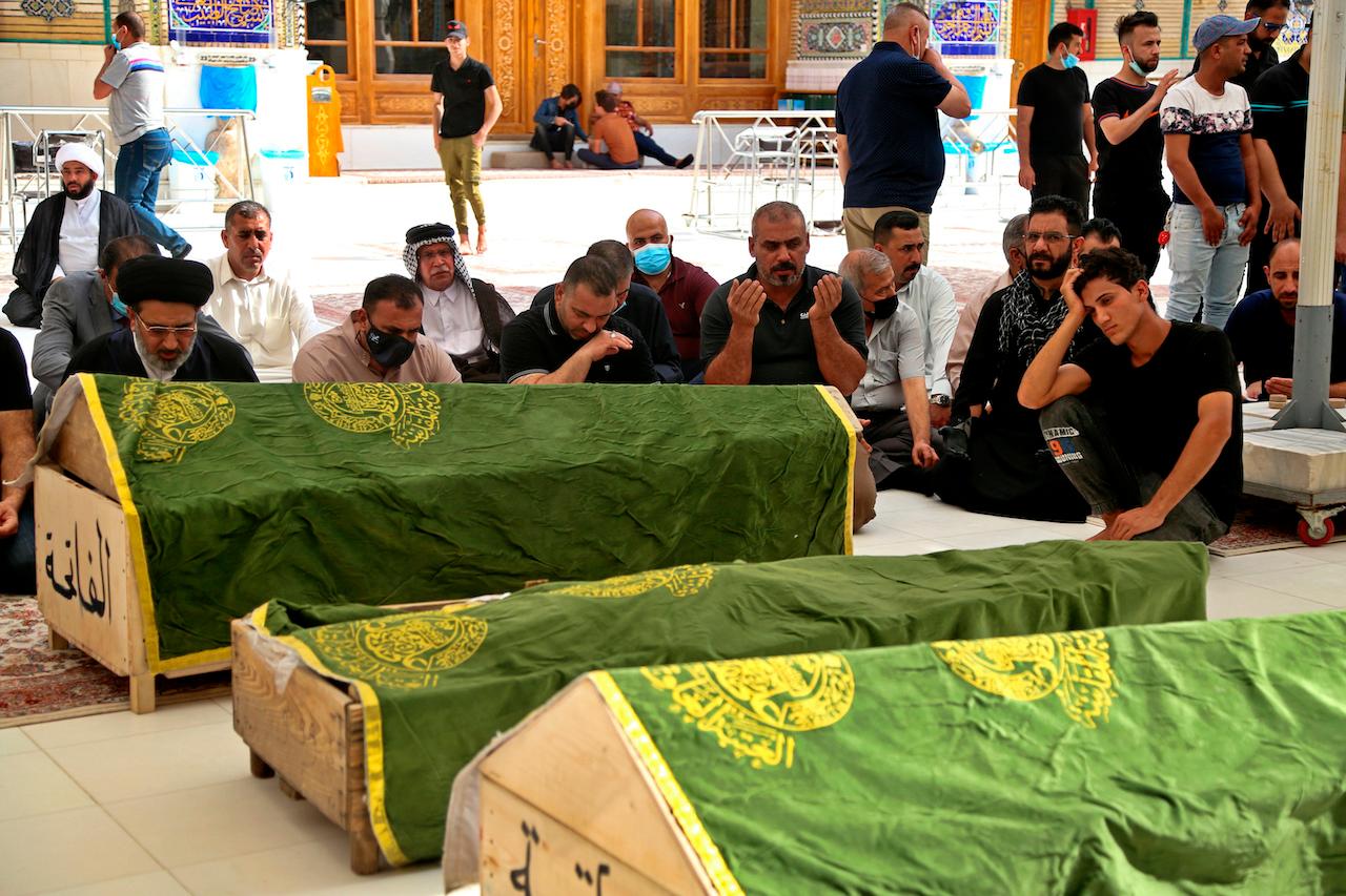Mourners pray near the coffins of Covid-19 patients who were killed in a hospital fire, during their funeral at the Imam Ali shrine in Najaf, Iraq, April 25. Iraq’s interior ministry said Sunday that over 80 people died and over 100 were injured in a catastrophic fire that broke out in the ICU of a Baghdad hospital tending to severe coronavirus patients. Photo: AP