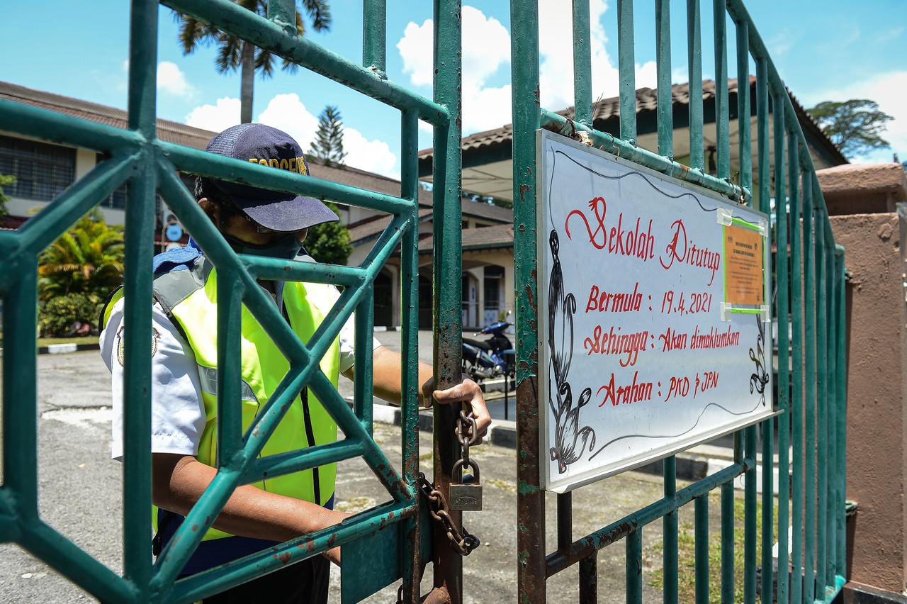 A security guard closes the gate of SK Bandar Baru Sri Damansara 2, one of 19 schools in Selangor which recently closed in the wake of an increase in Covid-19 cases. Photo: Bernama