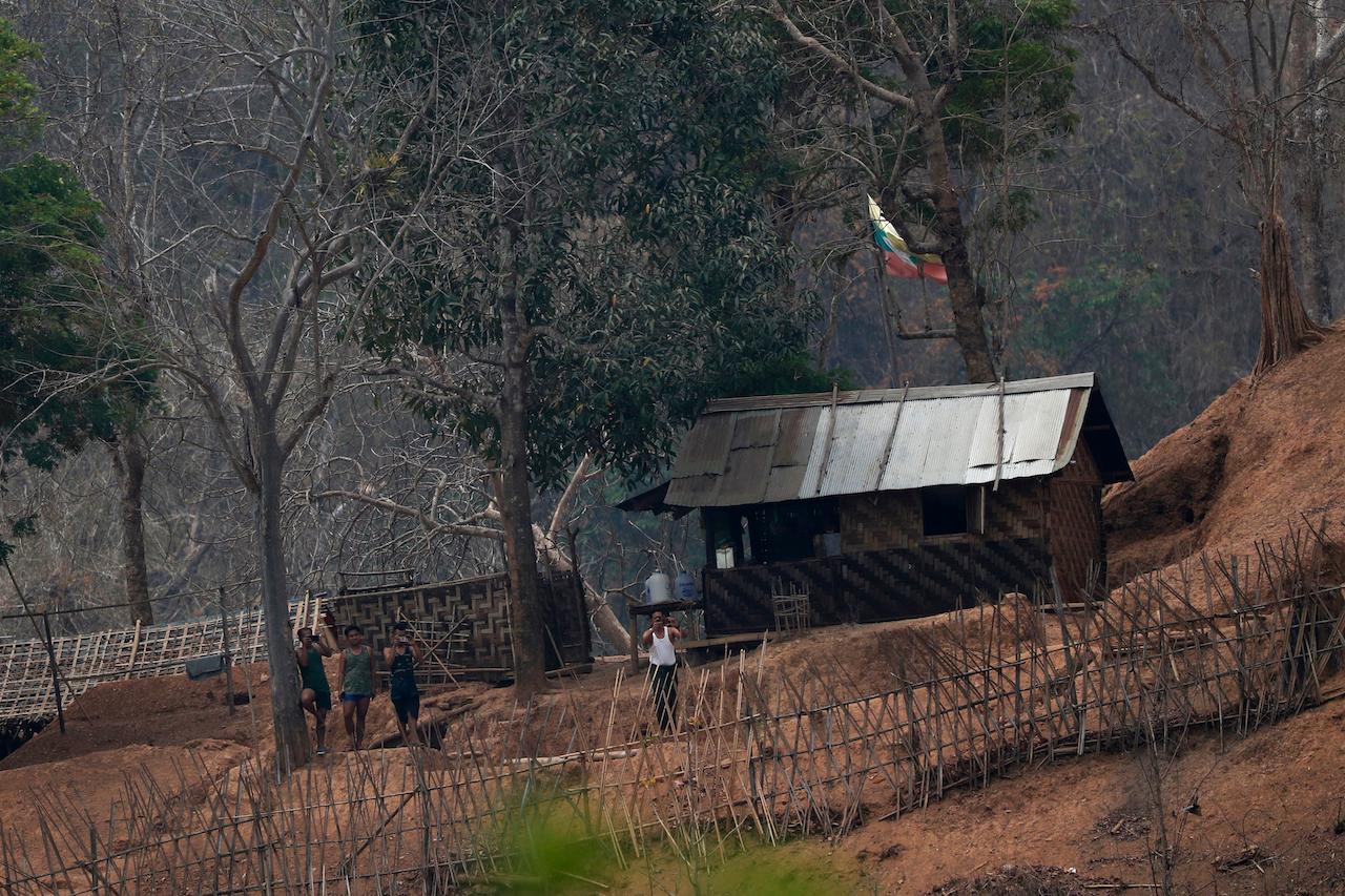 Myanmar soldiers stand at a small army camp along the river bank near the border of Myanmar and Thailand on March 30. Clashes have intensified in Karen state in recent weeks, displacing more than 24,000 civilians, including some 2,000 who crossed the river to seek refuge on the Thai side. Photo: AP