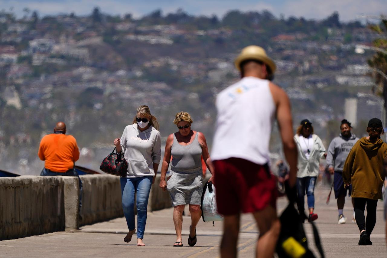 A woman who has been fully vaccinated walks with another who has yet to receive her jabs at a beach promenade in San Diego, California, April 27. US health officials say fully vaccinated Americans don't need to wear masks outdoors anymore unless they are in a big crowd of strangers. Photo: AP
