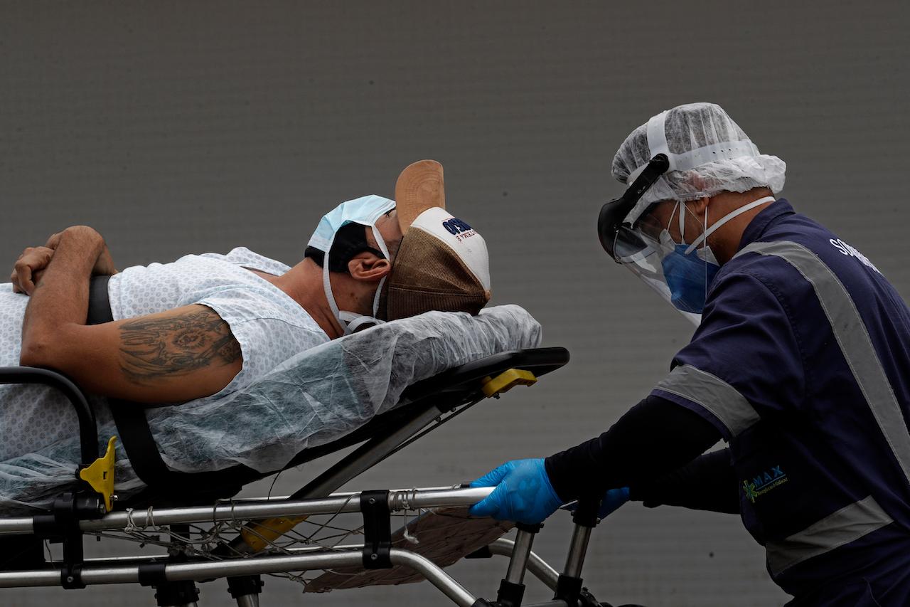 A healthcare worker transfers a patient suspected of having Covid-19 from an ambulance into the HRAN public hospital in Brasilia, Brazil, April 29. Photo: AP