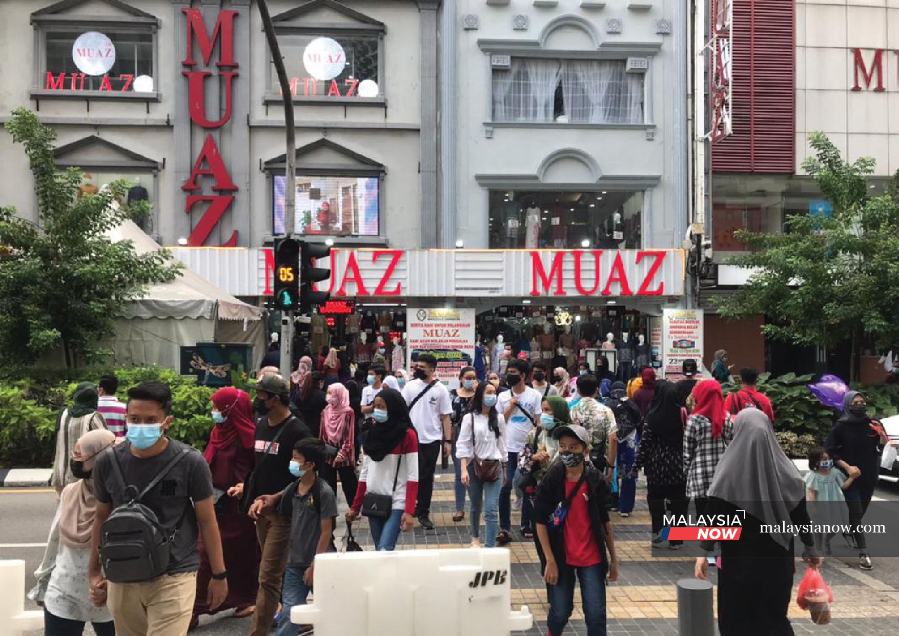 Crowds of people cross the road in front of a popular textile outlet in downtown Kuala Lumpur, as preparations for the Hari Raya celebration gather pace.
