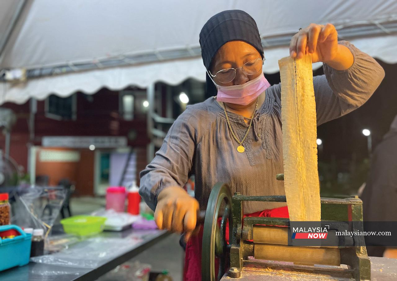 Dyg Zunika Abg Adenan uses a special machine to flatten the cuttlefish for suntong tutok at her stall in Kampung Nombor, Sarawak.
