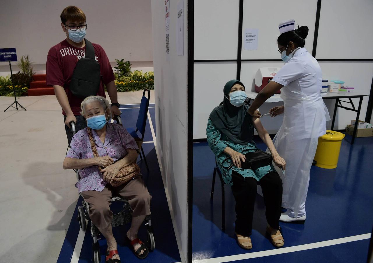 A senior citizen receives her first dose of Covid-19 vaccine while another waits for her turn at Dewan Muafakat Johor Taman Adda in Johor Bahru. Photo: Bernama