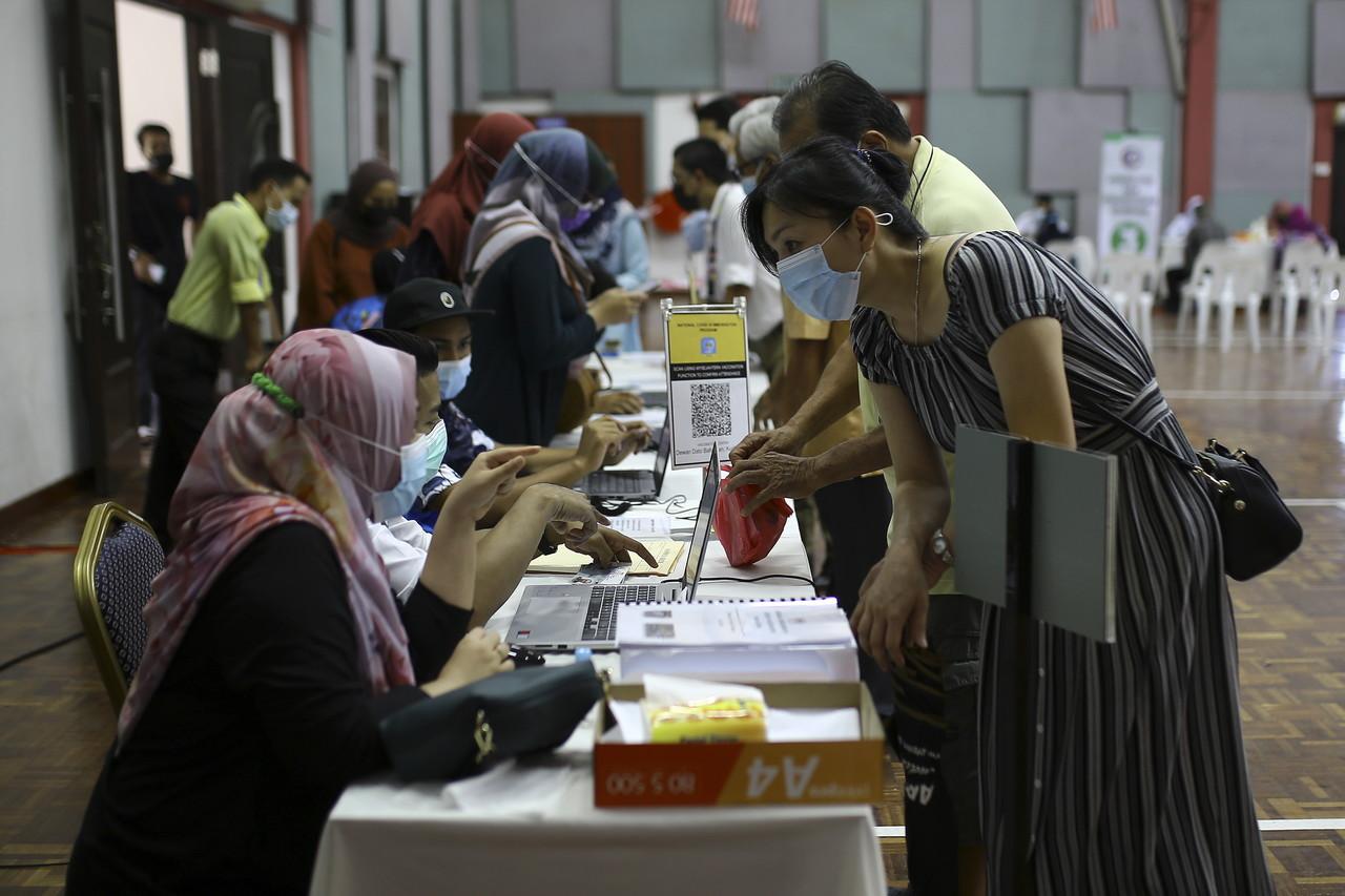 A woman registers an elderly parent for the Pfizer-BioNTech vaccine against Covid-19 under the second phase of the national immunisation programme at a hall in Kuala Pilah, Negeri Sembilan. Photo: Bernama