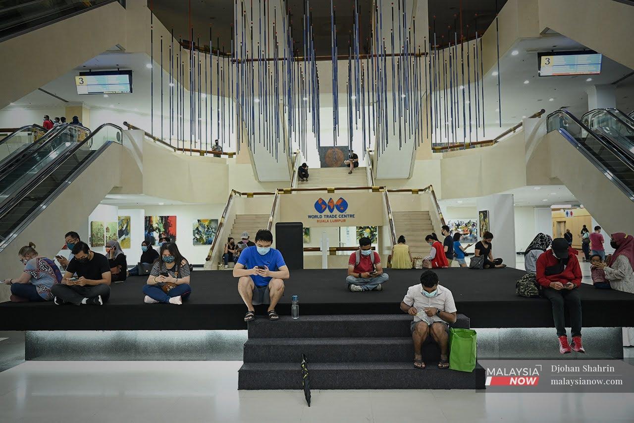 Beberapa penduduk Kuala Lumpur yang telah mendaftar secara sukarela menunggu waktu untuk mengambil suntikan vaksin AstraZeneca pada hari pertama ia dibuka di Pusat Dagangan Dunia Putra.