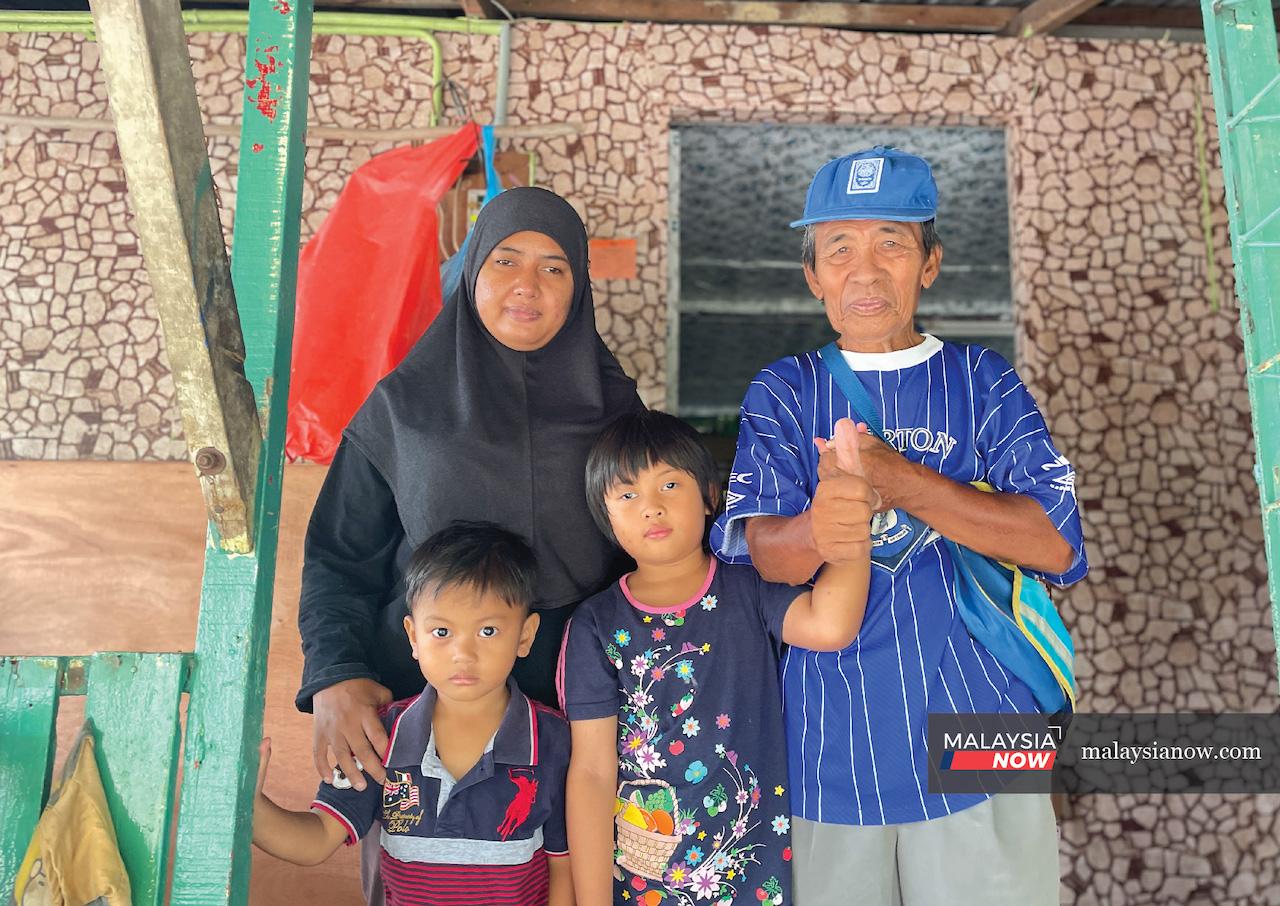 Siti Zaharah Abdullah (left) with her two children and her father-in-law, Puini Jaiman, outside their home in Kampung Gita Lama, Petrajaya, in Sarawak.