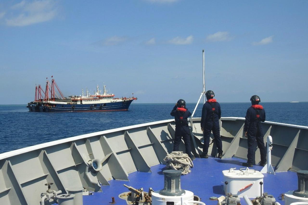 In this April 27 photo provided by the Philippine Coast Guard, its personnel patrol beside ships said to be Chinese militia vessels at Sabina Shoal in the South China Sea. The Philippine government has protested the Chinese coast guard's harassment of Philippine coast guard ships patrolling a disputed shoal in the South China Sea. Photo: AP