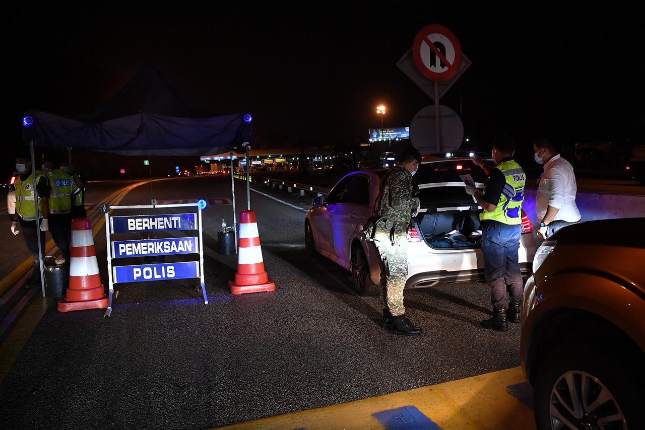 Police and members of the armed forces check a vehicle at a road block at the Gombak toll plaza heading to Kuala Lumpur last night, ahead of the movement control order which came into effect across much of Selangor today. Photo: Bernama